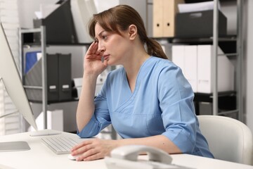 Obraz premium Tired nurse at desk in office. Medical worker