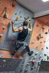 climber is navigating an indoor rock wall, skillfully using various holds. Bright colors and textured surfaces create a vibrant atmosphere for climbing practice