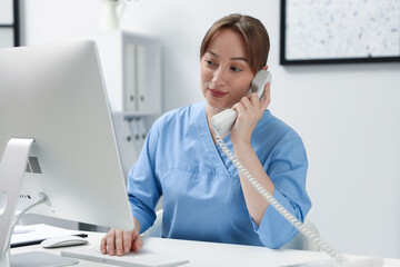 Nurse talking on telephone at desk in office