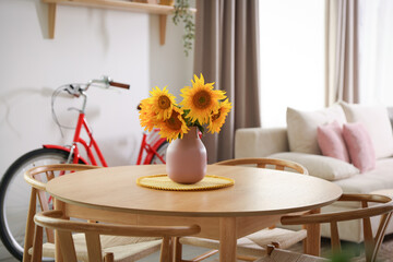 Wooden dining table with chairs, sofa and bicycle in room