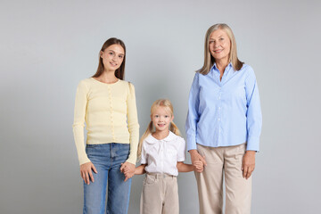 Little girl with her mother and grandmother on light background