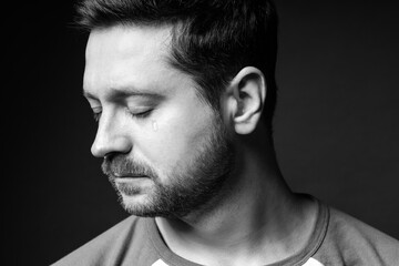 Sad man crying on dark background, black and white effect