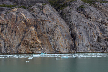 Rock formations nearby a small waterfall over floating ice caps in Alaska