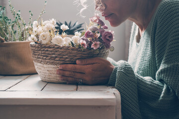 Woman at home arranging a bouquet of fresh flowers, smiling and serene in soft natural light,...