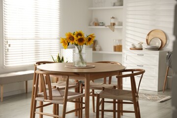 Beautiful sunflowers in vase on dining table at home