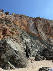 Rocky coastal landscape with steep cliffs and clear blue sky at midday