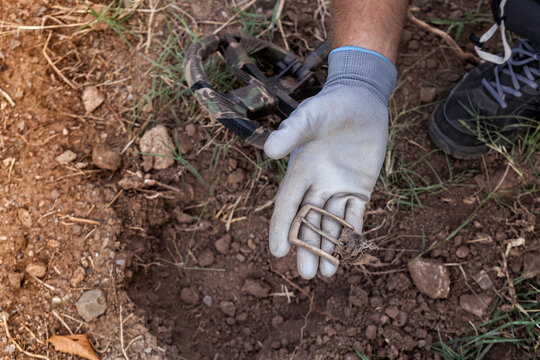 A man's hand with a metal detector holds a found buckle.