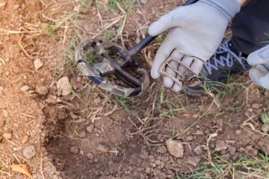 A man's hand with a metal detector holds a found buckle.