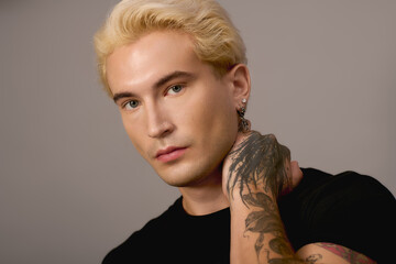 Stylish young man poses confidently with tattoos and trendy hairstyle