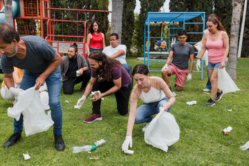 Group of diverse Latin people collecting trash in a public park in Mexico, Latin America. Group of multi age Hispanic volunteers cleaning up and collecting plastic in save the planet concept