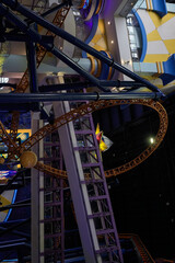 indoor amusement scene featuring roller coaster tracks, steel supports, and colorful walls, conveying energy and excitement