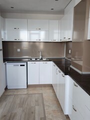 Modern minimalist white kitchen interior with glossy cabinets and appliances