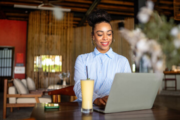 Happy freelancer enjoying a nutritious breakfast of smoothie and salad while working on a laptop