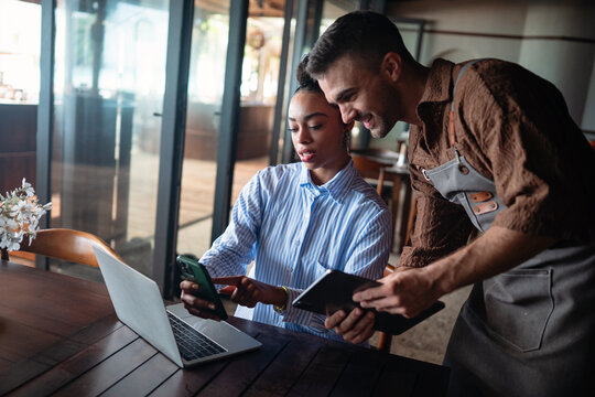 Collaborative cafe moment with waiter and businesswoman, freelancer using tech while working