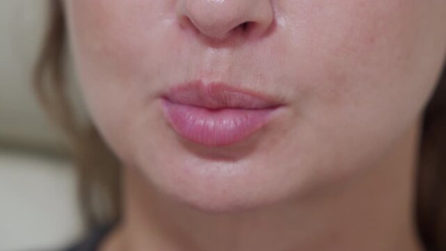 A close-up captures a woman puckering her lips, suggesting she's about to make a kissing sound.