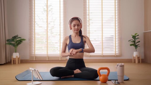 Asian woman practices yoga meditation at home listening music promoting wellness and inner peace with guided exercise for mental health