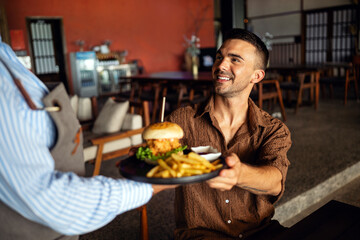 Waitress delivers a juicy burger in cozy restaurant setting with a warm smile and great hospitality