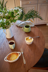 Cottage cheese souffle. Side view. A flowering branch in a vase. Souffle in a ramekin .