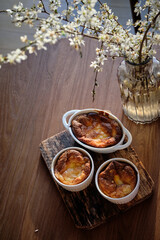 Cottage cheese souffle. Side view. A flowering branch in a vase. Souffle in a ramekin .