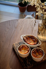 Cottage cheese souffle. Side view. A flowering branch in a vase. Souffle in a ramekin .