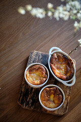 Cottage cheese souffle. Side view. A flowering branch in a vase. Souffle in a ramekin .