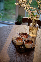 Cottage cheese souffle. Side view. A flowering branch in a vase. Souffle in a ramekin .