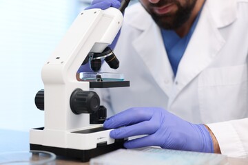 Research in genetics. Scientist working with microscope at table in laboratory, closeup