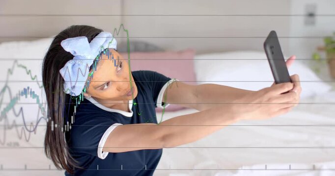 Adult female holding smartphone on bed and initiating transparent charts tracking stock growth