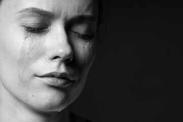 Sad woman crying on dark background, closeup. Black and white effect
