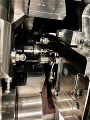 Close-up view of precision metal machinery components inside an industrial machine, showing detailed engineering design, stainless steel parts, and mechanical assembly in a modern factory.