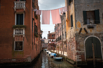 A typical canal in Venice, Italy, with boats tied up alongside and laundry strung between the buildings to dry. 