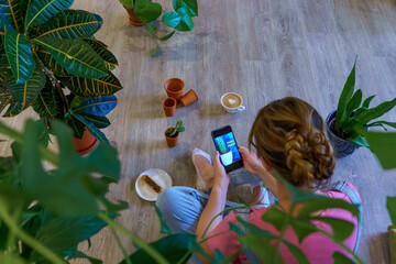A woman surrounded by several houseplants. 