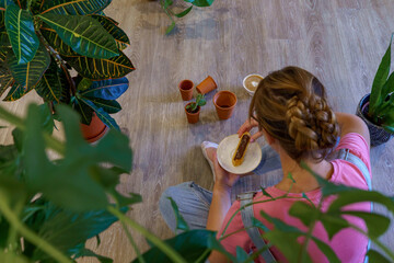 A woman surrounded by several houseplants. 