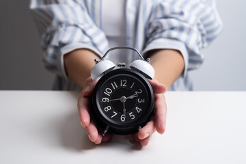 Woman holds an alarm clock. It's time to get up, time for morning rituals. 