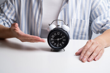 Woman holds an alarm clock. It's time to get up, time for morning rituals. 