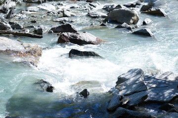 Flowing river water cascades over smooth stones, creating a serene natural landscape, with sunlight reflecting off the surface, embodying tranquility and harmony in nature