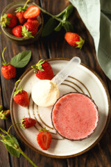 Fresh strawberry protein smoothie on a wooden table with fresh strawberries and a protein powder. Top view flat lay.