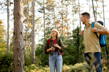 Fototapeta premium Two hikers enjoying the outdoors in a forest during a sunny day while taking a break from their trek