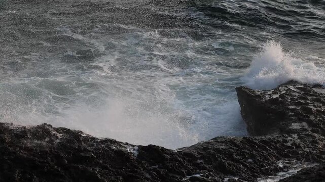 ocean waves crashing against rocky coastline slow motion 60fps 4k footage,nature landscape ocean water foam splash on rock cliff