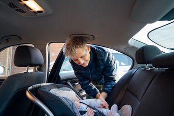 Father putting baby in safety car seat happy family vacation road trip lifestyle child care...