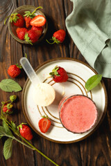 Fresh strawberry protein smoothie on a wooden table with fresh strawberries and a protein powder. Top view flat lay.