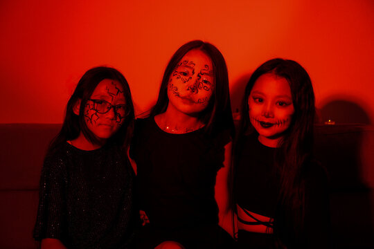 girls are sitting in room,with one of them holding a glowing carved pumpkin. - Powered by Adobe