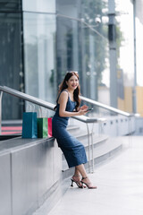 Naklejka premium beautiful asia woman female pleased positive casual shopping hand hold paper bags happy woman enjoy purchase cloths shopping buy sales discount at center mall store shopfront corridor department store