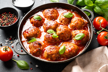 Meatballs in tomato sauce in iron plate on black background.