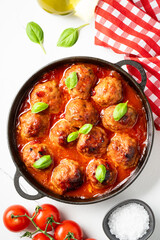 Meatballs in tomato sauce in iron plate on black background.