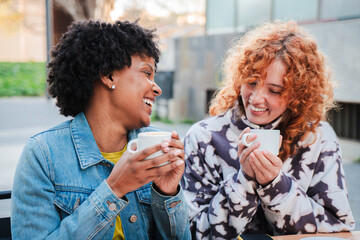 Two cheerful friends share smiles and laughter as they enjoy their coffee together in a lively outdoor cafe atmosphere, creating unforgettable moments filled with joy and connection.