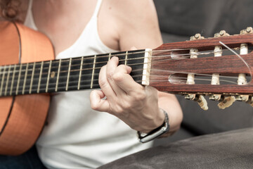 Obraz premium Woman playing classical guitar, pressing chords on fretboard