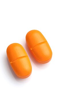 Two vibrant orange pills on a white background