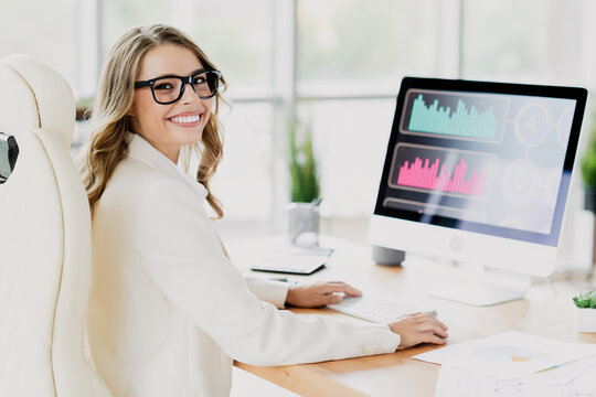Businesswoman working in modern office analyzing data graphs on computer screen representing success and productivity