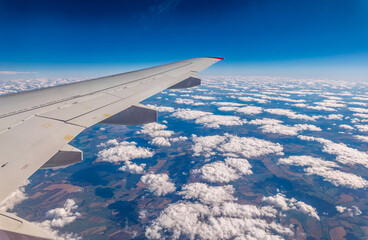 Obraz premium View from the airplane window at a beautiful cloudy sky and the airplane wing